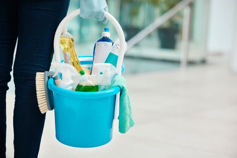 Cleaner carrying a bucket full of cleaning supplies to a location to clean